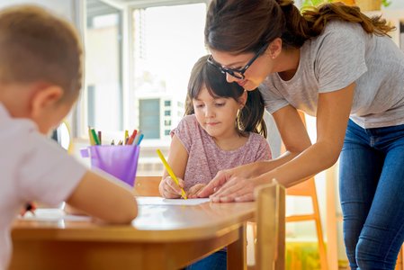 Lehrerin hilft Schülerin beim Schreiben