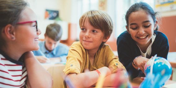 Kinder im Schulzimmer mit Globus und Stiften