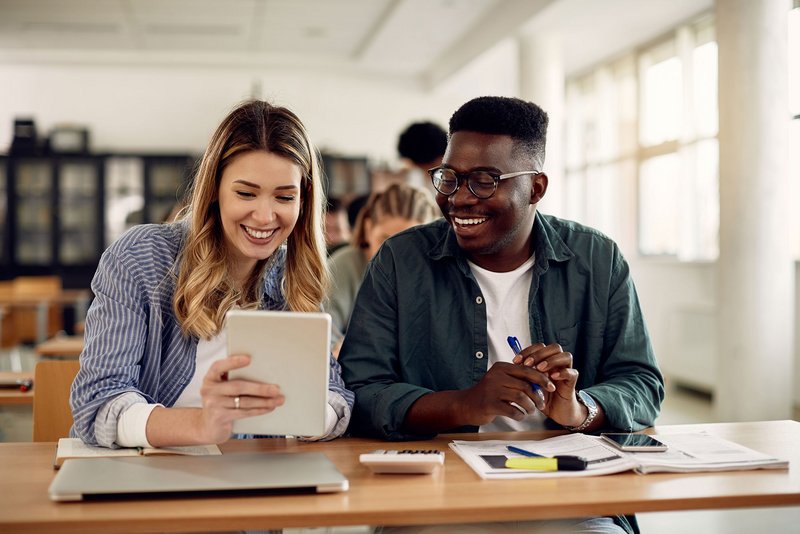 Schülerin und Schüler mit Tablet und Laptop in einem Klassenraum